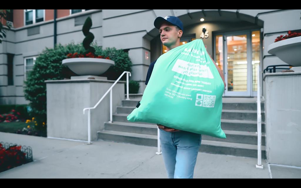 A Laundry King driver collecting a laundry bag from a customer's door in Brooklyn